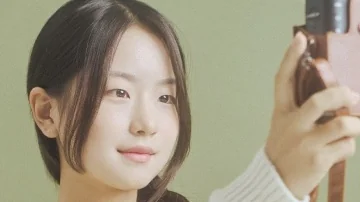 밝은 니트 차림으로 촬영 기기를 든 모델의 사진